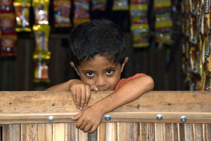 This boy's curiousity eventually got the better of him, and he peered over the rail of his mother's roadside stall.
