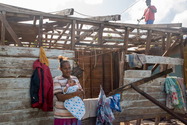 Wilma holds her baby, Francois, in the middle of their family home on Ifira island. It is still in need of major renovations three months after cyclone Pam caused extensive damage.
