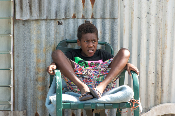 A boy watches as workers repair his home on Ifira island. The house was badly damaged by cyclone Pam.
