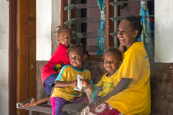 Eva and her children smile as they sit outside the community clinic on Ifira island.
