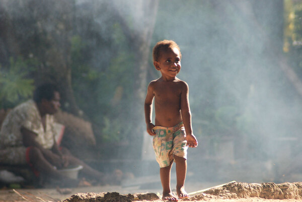 A child emerges from the smoke of the cookfire
and runs to greet his father.
