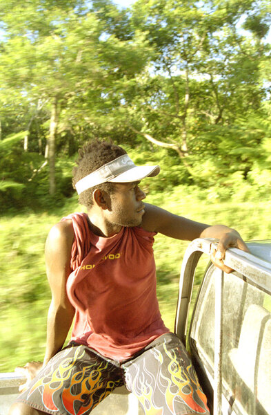 No sooner did my friend Stephen announce that he was driving
across Tanna to see the volcano, than we found ourselves hosts
to about half a dozen passengers travelling to various villages
along the road.
This young man from White Sands and I joked and laughed all the way
down the (very) rutted road. I'm frankly amazed that a photo
taken one-handed in the back of a speeding truck could have worked.
I decided the try shooting the view from the back of the truck
because it represents most of what an island traveler ever
sees.

