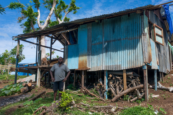 Rachel's father stands in front of the makeshift house they built for the land-owner out of salvaged parts.
