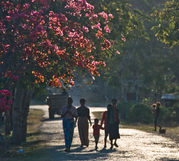 Women walk home through the afternoon light.

