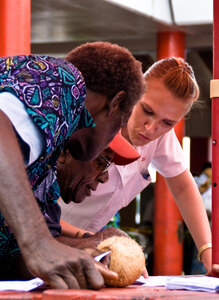 Digicel's Carissa Brown shows two men from North Efate how to configure their phone for GPRS service.
