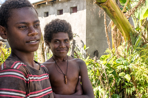 A young woman smiles in wreckage the day after cyclone Pam destroyed her mother's handicrafts stall at Port Vila's seafront. In the background is a sign exhorting people to keep Port Vila clean.
