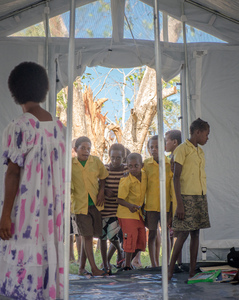 A young woman smiles in wreckage the day after cyclone Pam destroyed her mother's handicrafts stall at Port Vila's seafront. In the background is a sign exhorting people to keep Port Vila clean.
