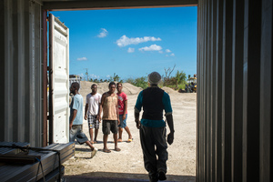 A young woman smiles in wreckage the day after cyclone Pam destroyed her mother's handicrafts stall at Port Vila's seafront. In the background is a sign exhorting people to keep Port Vila clean.
