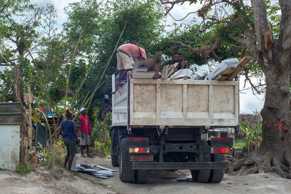 A young woman smiles in wreckage the day after cyclone Pam destroyed her mother's handicrafts stall at Port Vila's seafront. In the background is a sign exhorting people to keep Port Vila clean.
