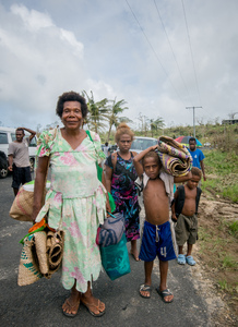A young woman smiles in wreckage the day after cyclone Pam destroyed her mother's handicrafts stall at Port Vila's seafront. In the background is a sign exhorting people to keep Port Vila clean.
