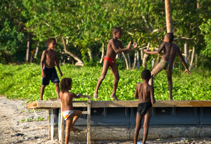A group of young boys position themselves to defend their possession of walking-about rights on a beached pontoon.
