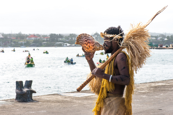 A Futunese warrior blows a conch shell trumpet to welcome a flotilla of small craft during the ground-breaking ceremony for the Lapetasi wharf project.
