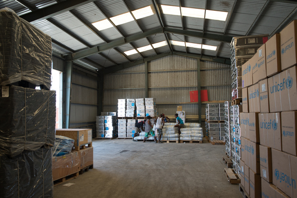 Staff and volunteers wrangle over 90 tonnes of newly arrived emergency supplies at the UNICEF warehouse near Port Vila, Vanuatu. The influx of supplies required the construction of a new temporary storage facility as well.
