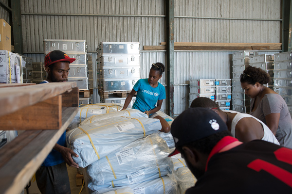 Staff and volunteers wrangle over 90 tonnes of newly arrived emergency supplies at the UNICEF warehouse near Port Vila, Vanuatu. The influx of supplies required the construction of a new temporary storage facility as well.
