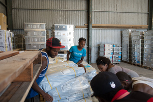 Staff and volunteers wrangle over 90 tonnes of newly arrived emergency supplies at the UNICEF warehouse near Port Vila, Vanuatu. The influx of supplies required the construction of a new temporary storage facility as well.
